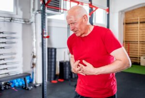 homme senior qui a une douleur intercostale dans une salle de sport